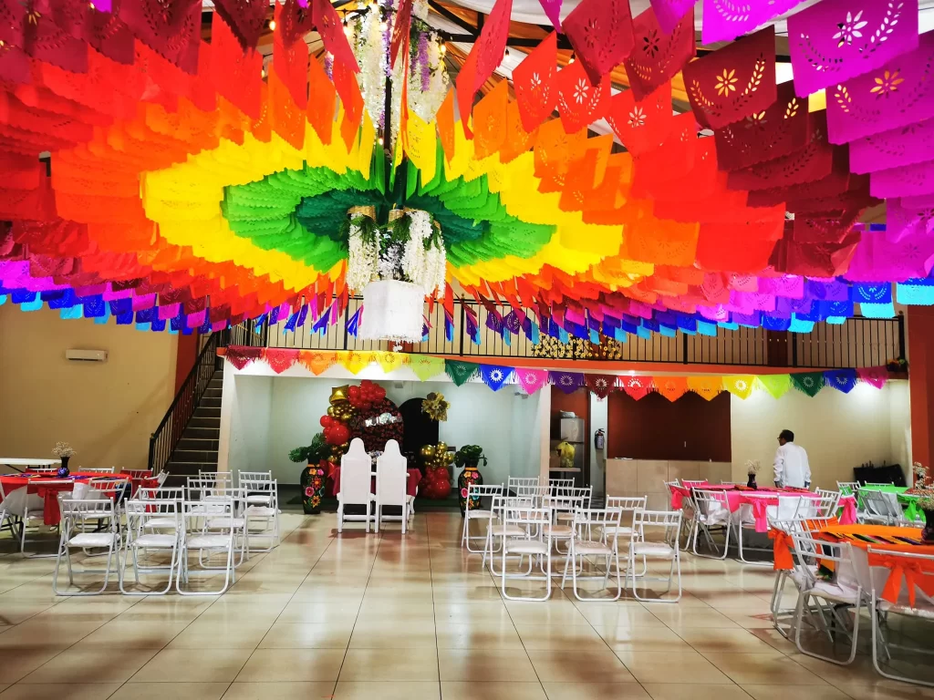 Salón decorado con papel picado de colores en el techo
