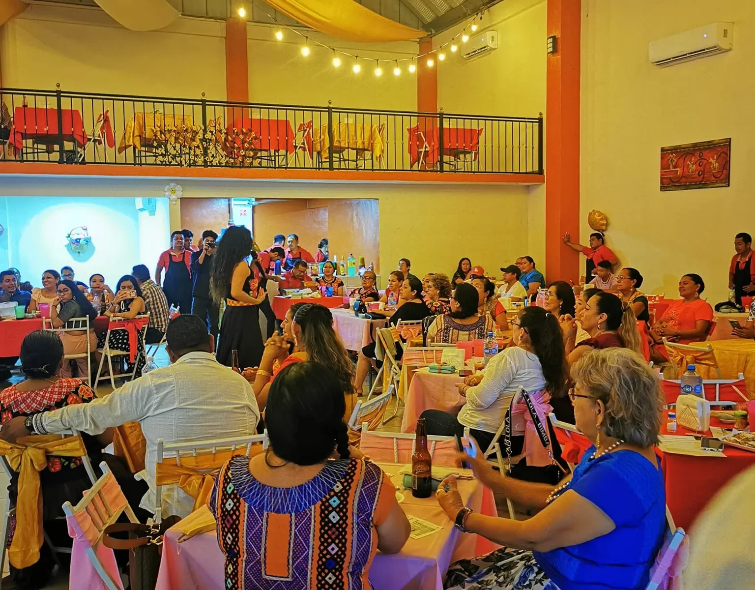 Invitados disfrutando de una fiesta en un salón decorado con telas y luces cálidas