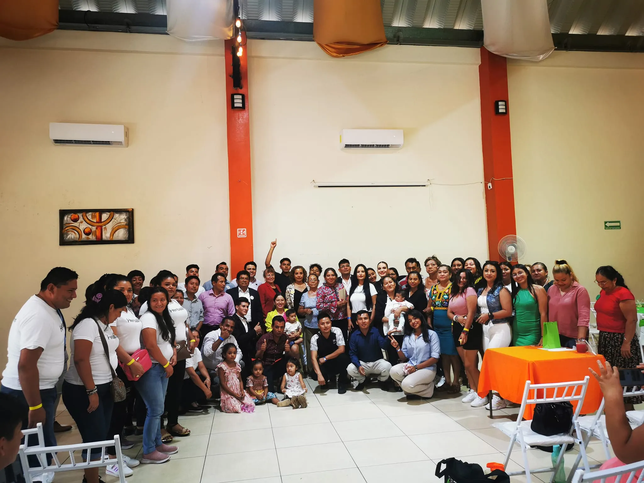 Grupo de personas reunidas en un salón de eventos con decoración colorida