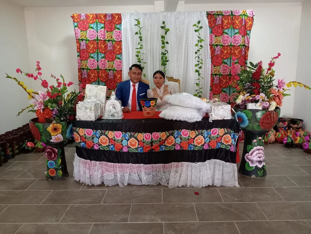 Pareja de recién casados sentados en una mesa decorada con detalles tradicionales