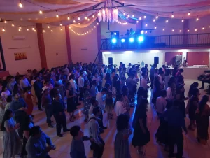 Fiesta nocturna con personas bailando en un salón iluminado con luces azules