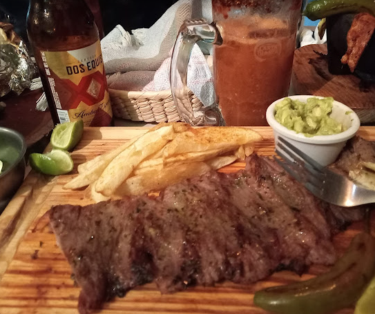 Plato de arrachera con papas fritas, guacamole, cerveza artesanal y michelada, servido en Moonlight Café Terraza en Salina Cruz, Oaxaca.