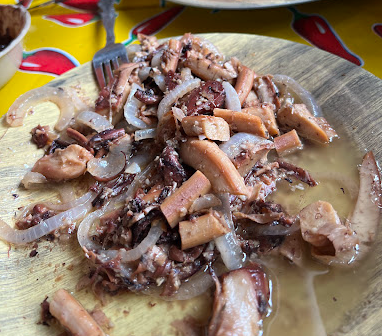 Pulpo al ajillo estilo istmeño con cebolla salteada, servido en plato de madera en La Cocina de Grecia, Magdalena Tlacotepec, Oaxaca.