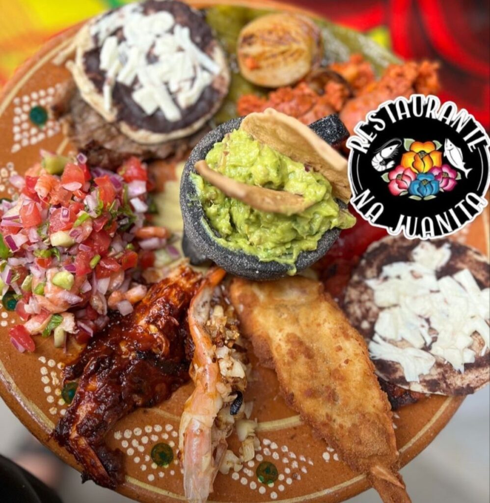 Platillo variado del Restaurante Na’ Juanita en Lachigoló, Oaxaca, con guacamole, picadillo, mariscos, tlayudas pequeñas, pico de gallo, queso y salsas típicas del Istmo.