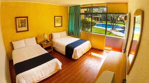 Habitación doble con vista a la alberca, decoración cálida y ventanales amplios en el Hotel Cali