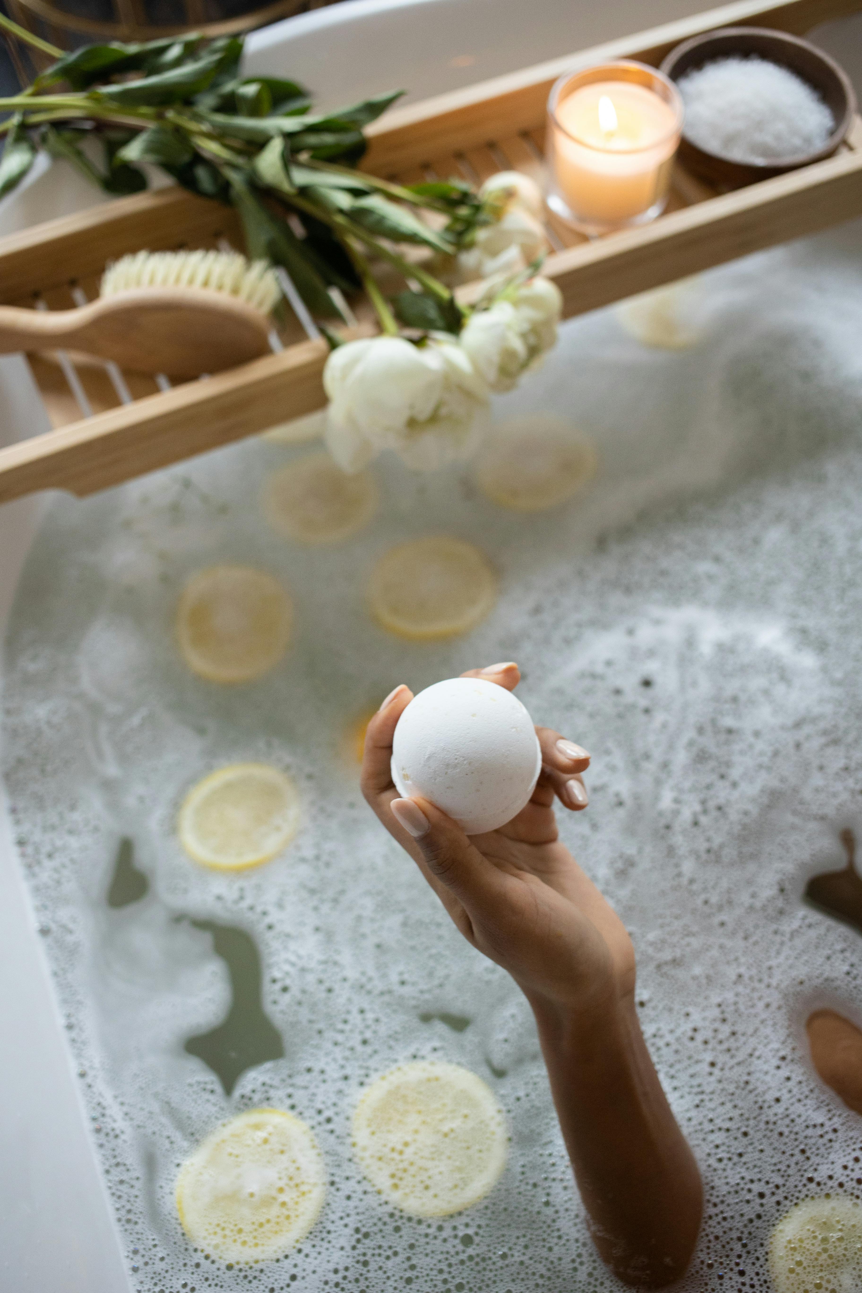 Momento de relajación con bomba de baño en tina con limón y flores