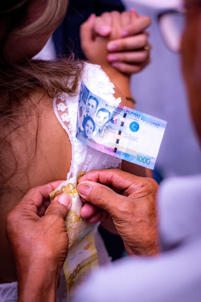Manos colocando billetes en el vestido de la novia durante el baile del billete, tradicional ritual de boda que simboliza prosperidad y buenos deseos para los recién casados