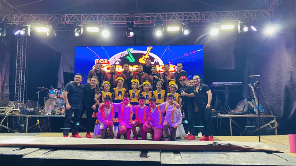 Los Soberanos posando junto a bailarines y bailarinas tradicionales después del show