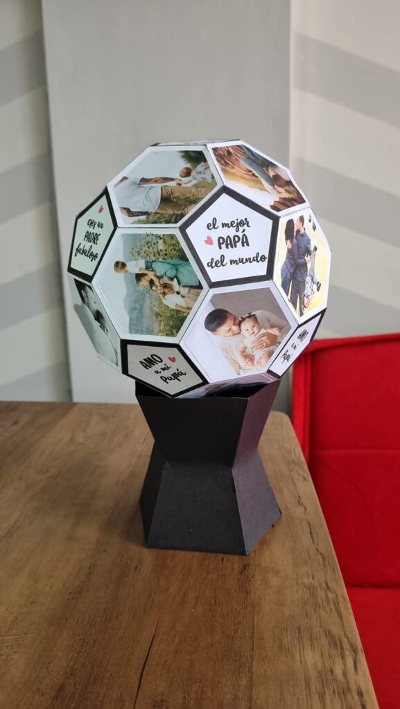 Esfera tipo balón decorada con fotos familiares y frases como “el mejor papá del mundo” y “amo a mi papá”, sobre base negra.