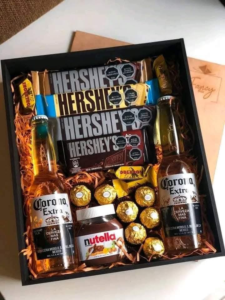 Caja de regalo con dos cervezas, barras de chocolate Hershey’s, Ferrero Rocher y un frasco de Nutella.
