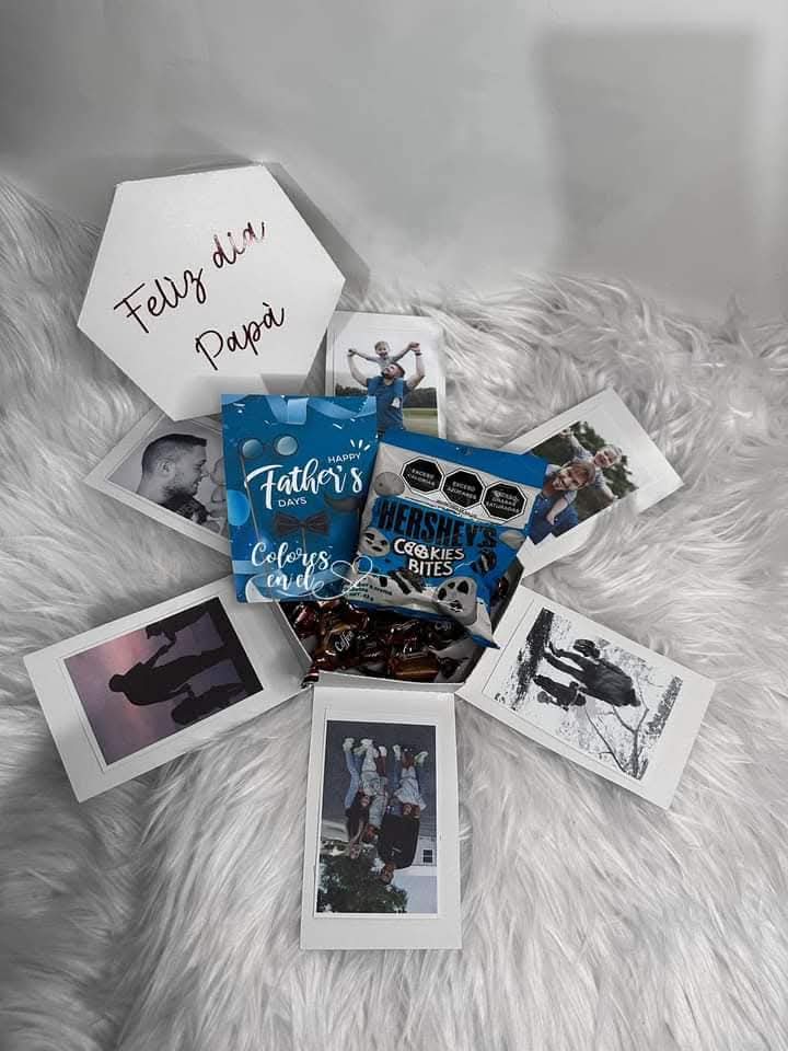 Caja explosiva con fotos familiares, dulces y un cartel con la frase “Feliz día Papá” sobre fondo blanco y peluche decorativo.