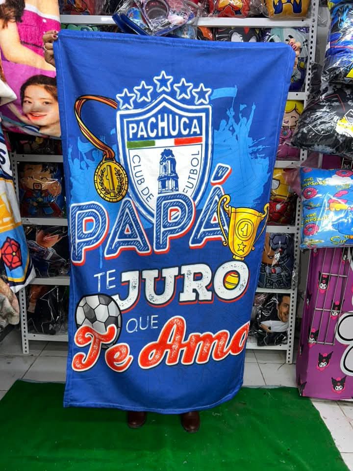 Cobija azul del Club Pachuca con la frase “Papá, te juro que te amo”, con diseño de balón y trofeo.