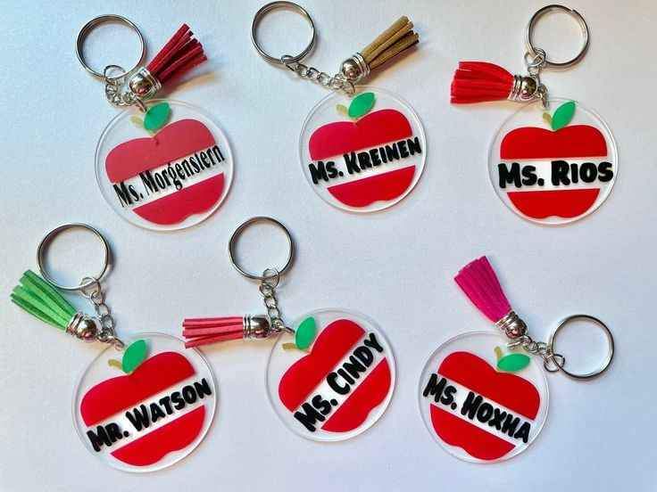 Llavero con forma de manzana roja y nombres de maestros como Ms. Cindy, Mr. Watson.