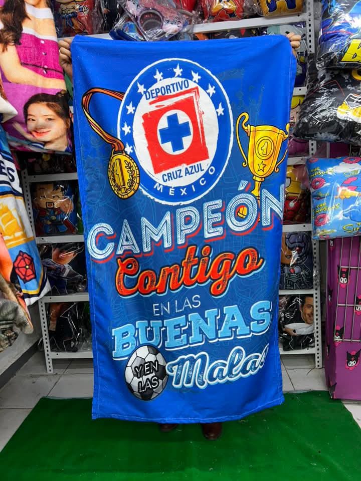 Cobija azul del Cruz Azul con la frase “Campeón contigo en las buenas y en las malas” y diseño de balón.